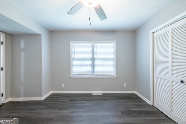 unfurnished bedroom with dark wood-type flooring, ceiling fan, and a closet