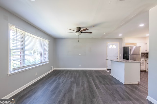 kitchen featuring white cabinets, dark wood-type flooring, stainless steel fridge, and a wealth of natural light