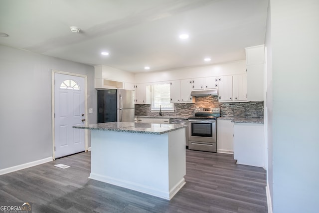 kitchen with appliances with stainless steel finishes, light stone counters, white cabinets, and dark hardwood / wood-style floors