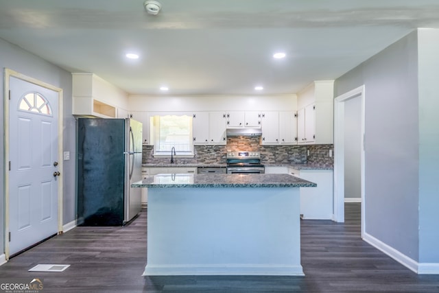 kitchen featuring white cabinets, dark wood-type flooring, a kitchen island, stainless steel appliances, and decorative backsplash