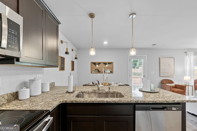 kitchen with light stone counters, sink, hanging light fixtures, appliances with stainless steel finishes, and dark brown cabinetry