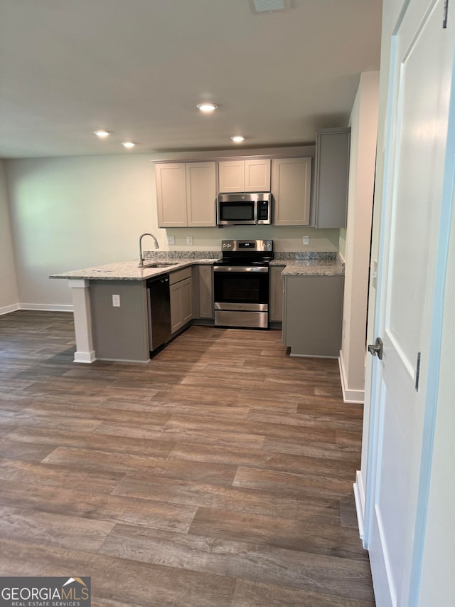 kitchen featuring wood-type flooring, gray cabinets, appliances with stainless steel finishes, and kitchen peninsula