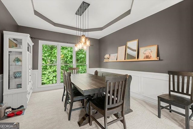 dining space featuring a notable chandelier, light colored carpet, and a tray ceiling