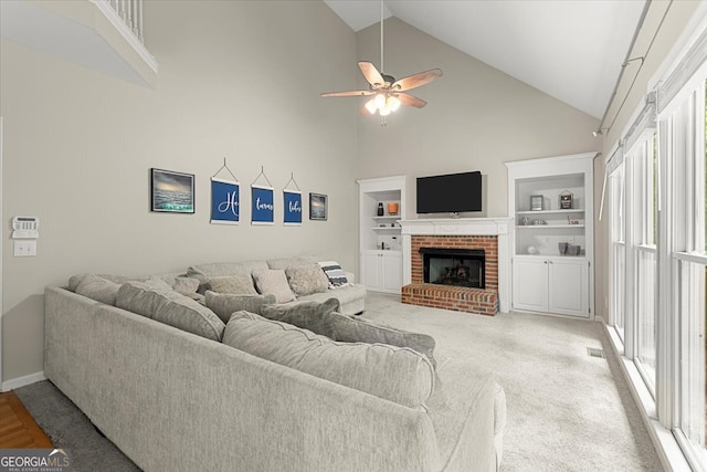 living room with a fireplace, ceiling fan, built in shelves, high vaulted ceiling, and carpet floors