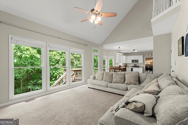 carpeted living room with ceiling fan and high vaulted ceiling