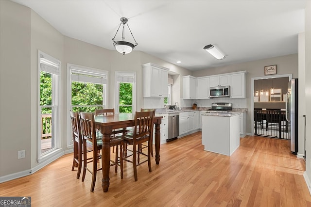 dining space featuring light hardwood / wood-style floors, sink, and a wealth of natural light