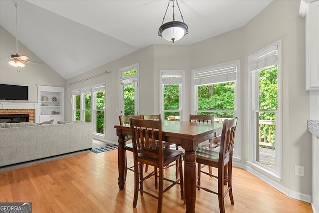 dining room featuring light hardwood / wood-style flooring, a fireplace, ceiling fan, and plenty of natural light