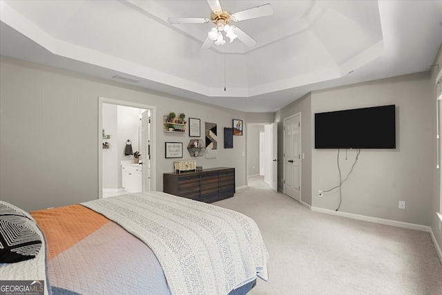 bedroom with ceiling fan, light carpet, connected bathroom, and a raised ceiling