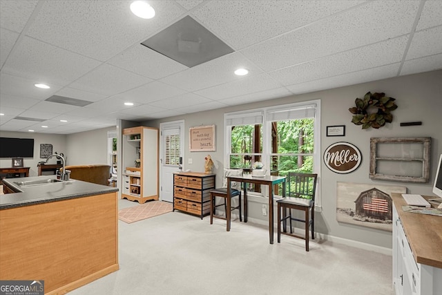 home office with light colored carpet, sink, and a paneled ceiling