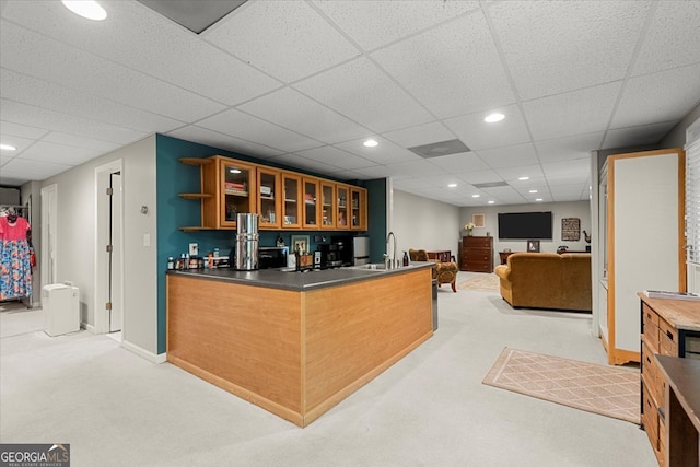 kitchen featuring light carpet, a drop ceiling, kitchen peninsula, and sink