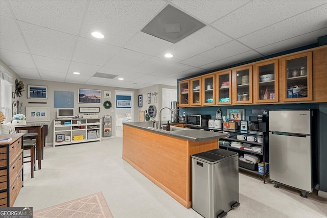 kitchen with refrigerator, light carpet, a paneled ceiling, stainless steel fridge, and sink