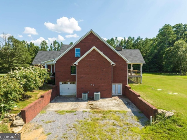 back of house featuring central AC unit, a garage, and a yard