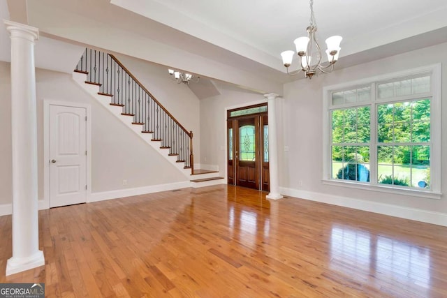 entryway with a chandelier, light wood-type flooring, and ornate columns