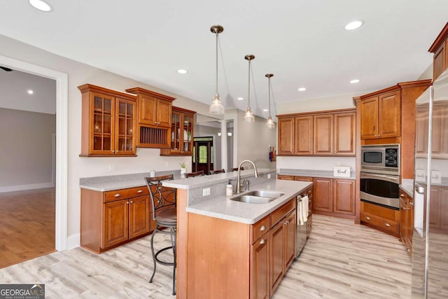 kitchen featuring hanging light fixtures, light wood-type flooring, sink, a breakfast bar, and appliances with stainless steel finishes