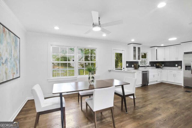 dining area with ceiling fan, dark wood-type flooring, sink, and ornamental molding