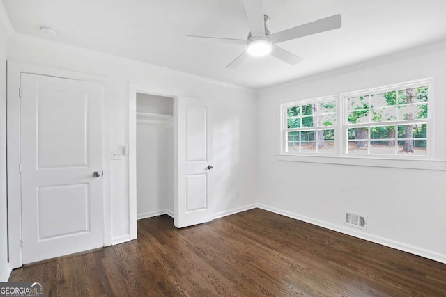 unfurnished bedroom featuring a closet, dark hardwood / wood-style floors, crown molding, and ceiling fan