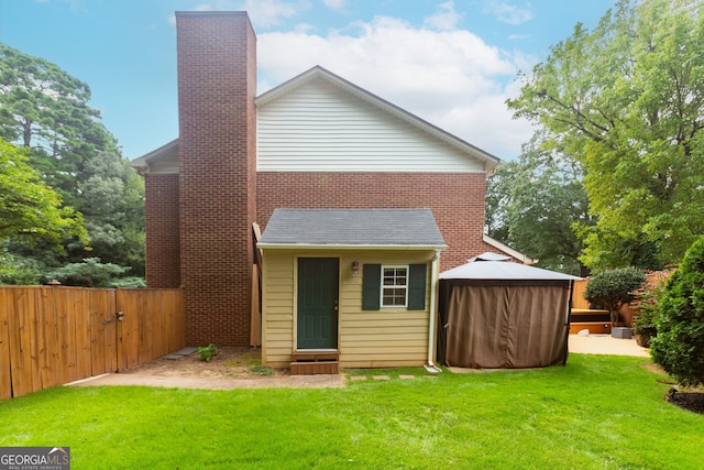 back of house with a gazebo and a lawn