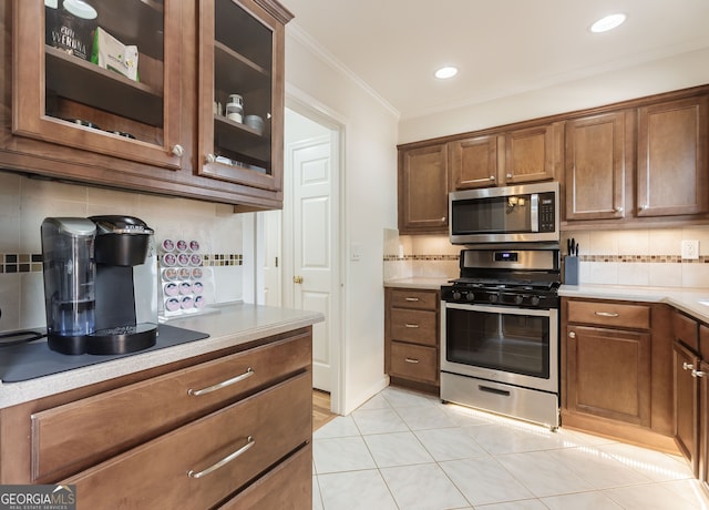 kitchen featuring light tile patterned floors, stainless steel appliances, tasteful backsplash, and ornamental molding