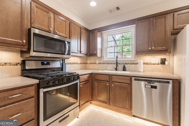 kitchen featuring light tile patterned floors, sink, appliances with stainless steel finishes, and tasteful backsplash