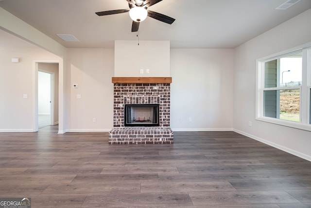 unfurnished living room with ceiling fan, a fireplace, and dark wood-type flooring