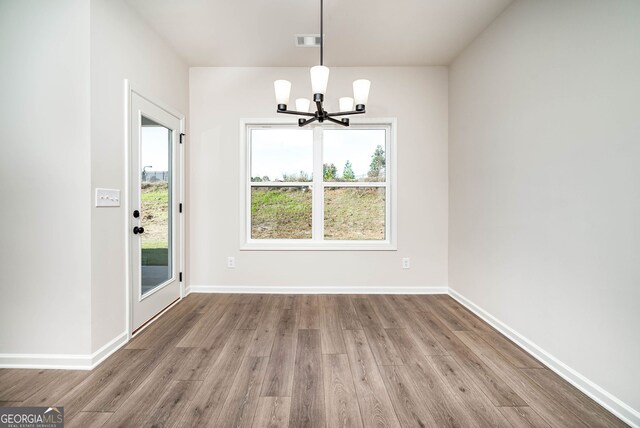 unfurnished dining area with a chandelier and hardwood / wood-style floors