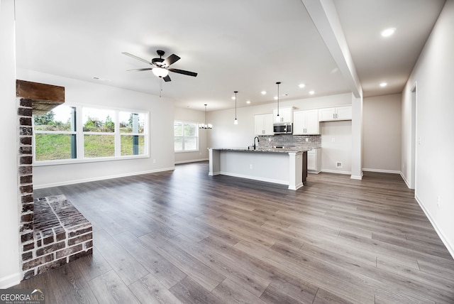 unfurnished living room with ceiling fan with notable chandelier, hardwood / wood-style flooring, and sink