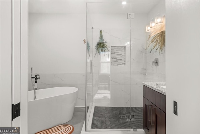 bathroom with tile walls, separate shower and tub, and vanity