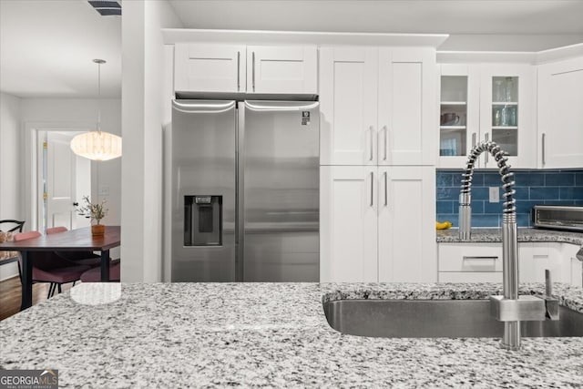 kitchen featuring white cabinets, stainless steel fridge, and tasteful backsplash