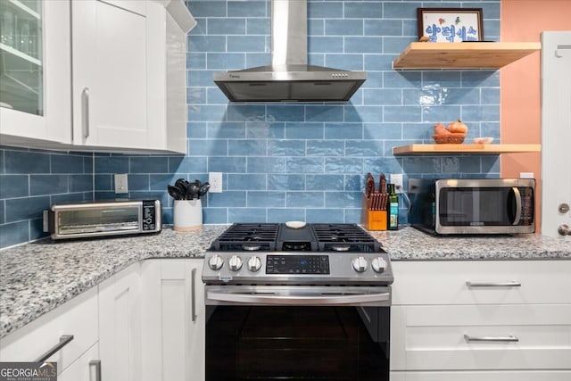 kitchen with decorative backsplash, appliances with stainless steel finishes, wall chimney exhaust hood, and white cabinets