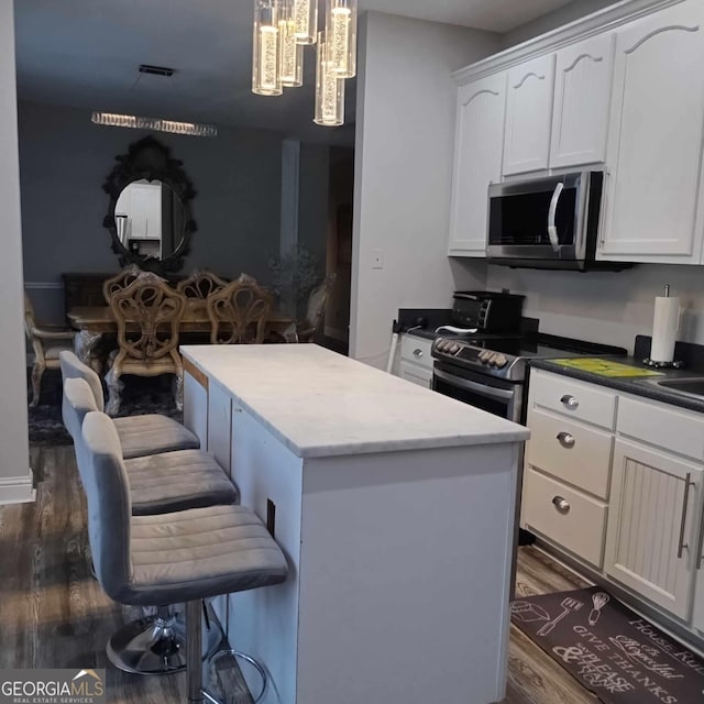 kitchen featuring appliances with stainless steel finishes, dark hardwood / wood-style floors, a kitchen island, and white cabinetry