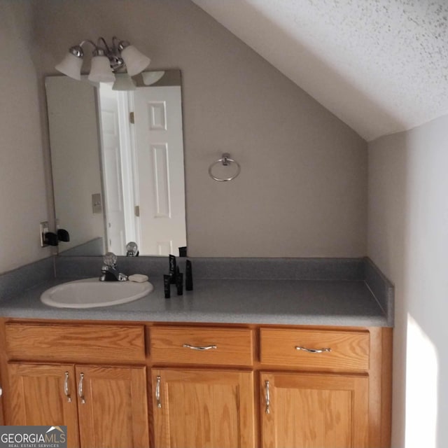 bathroom featuring a textured ceiling, vanity, and vaulted ceiling