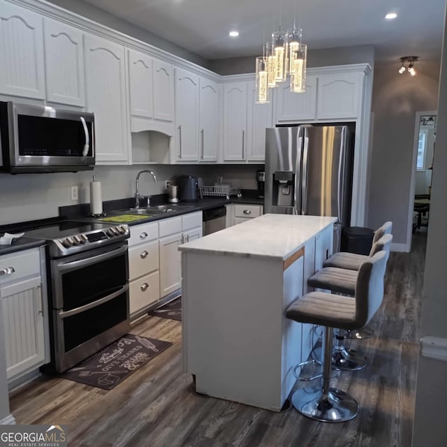 kitchen with dark hardwood / wood-style floors, white cabinets, a kitchen island, stainless steel appliances, and sink