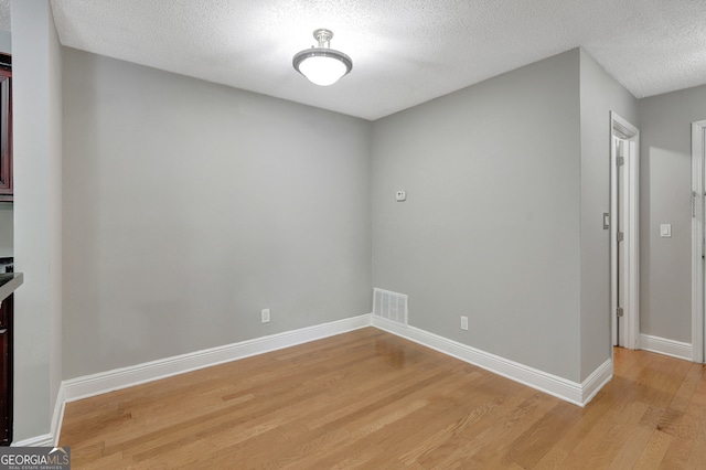 empty room featuring light wood-type flooring and a textured ceiling