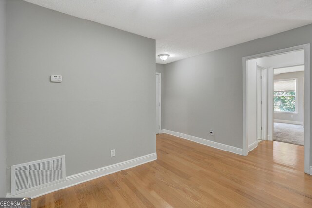 empty room with a textured ceiling and light hardwood / wood-style floors