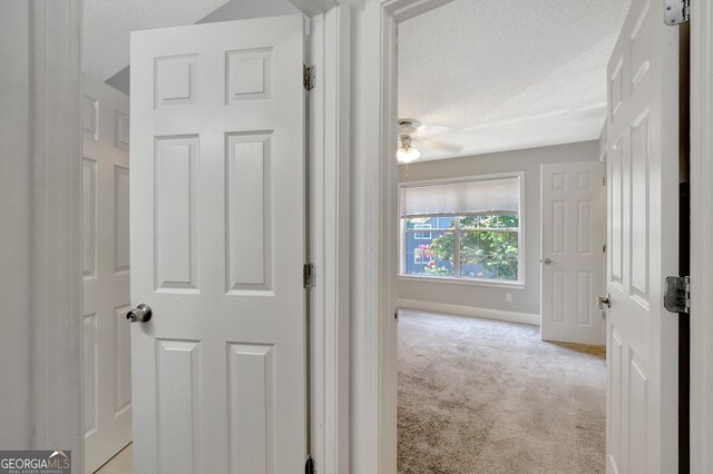 hallway featuring light carpet and a textured ceiling