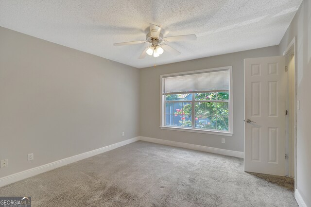 unfurnished room with a textured ceiling, ceiling fan, and light carpet