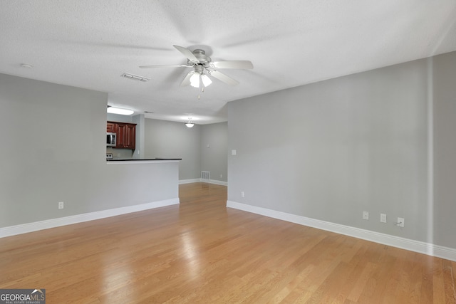 empty room with a textured ceiling, wood-type flooring, and ceiling fan