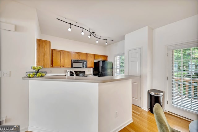 kitchen featuring black appliances, a healthy amount of sunlight, rail lighting, and light wood-type flooring