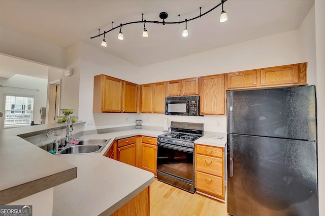 kitchen with black appliances, sink, kitchen peninsula, light hardwood / wood-style floors, and rail lighting