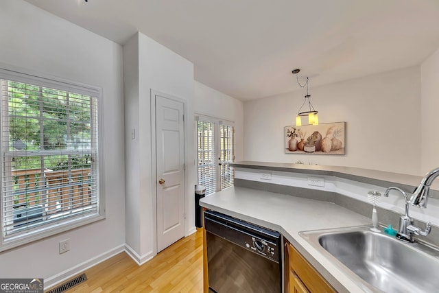 kitchen with dishwasher, light hardwood / wood-style flooring, sink, and pendant lighting