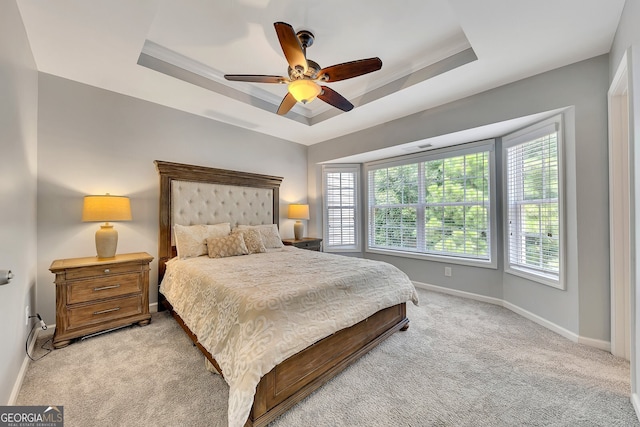 bedroom featuring ceiling fan, light carpet, and a tray ceiling