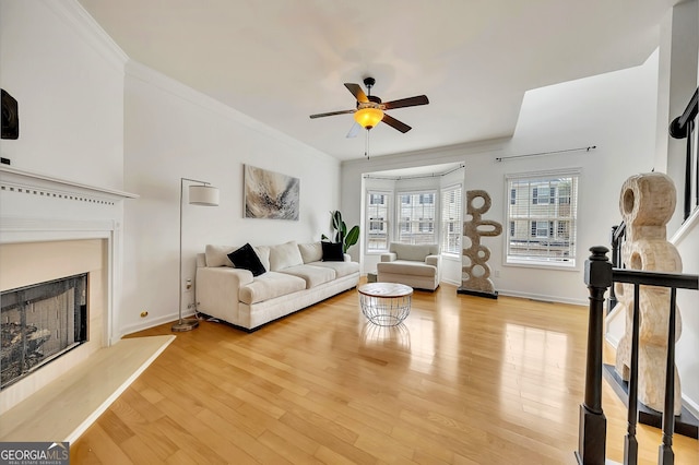 living room with ceiling fan, crown molding, and light hardwood / wood-style flooring