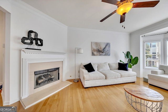 living room with ornamental molding, ceiling fan, and light wood-type flooring