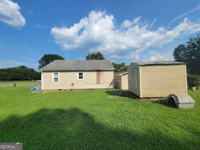 rear view of house with a storage shed, a lawn, and an outbuilding