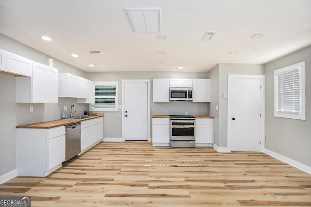 kitchen featuring light hardwood / wood-style flooring, white cabinetry, stainless steel appliances, sink, and butcher block counters