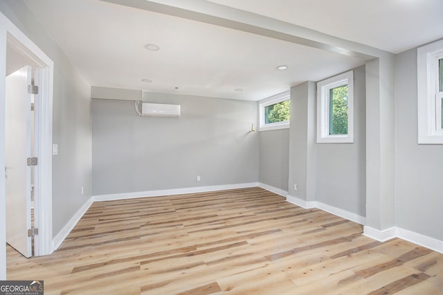 unfurnished room with light wood-type flooring and a wall unit AC