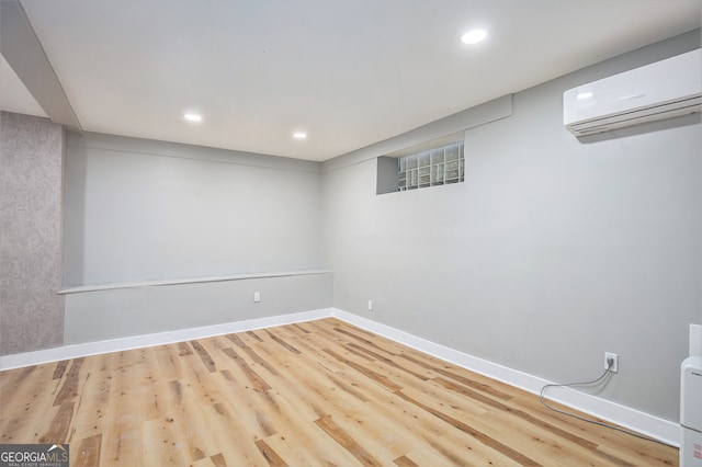 basement with light wood-type flooring and a wall mounted AC