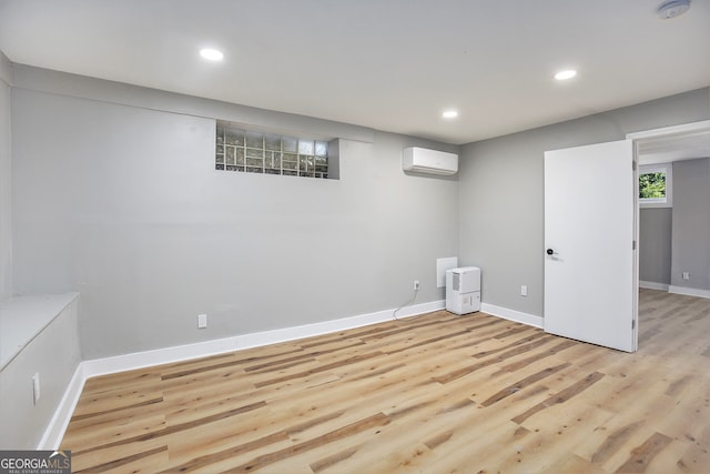 basement with light hardwood / wood-style flooring and a wall unit AC