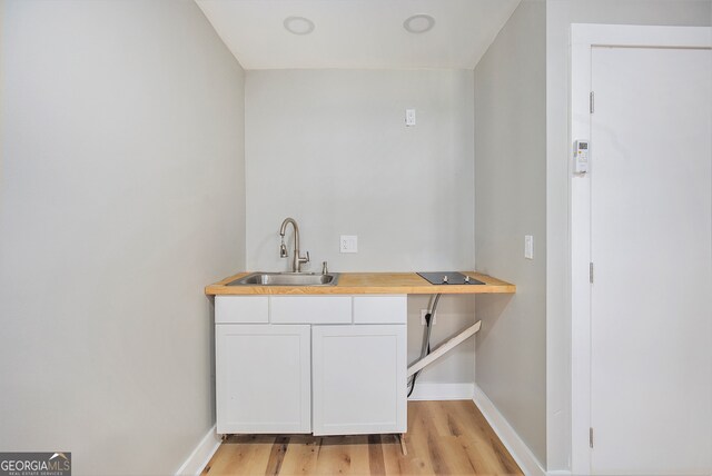 bar featuring sink, white cabinets, and light hardwood / wood-style floors