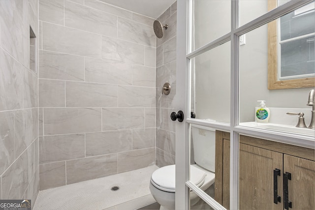 bathroom featuring vanity, a tile shower, and toilet